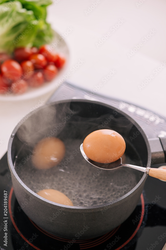 厨师把煮鸡蛋放在杯子里/烹饪甜褐色炖猪肉肉汁（Moo Pa lo）概念