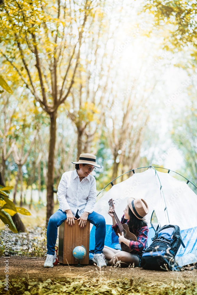 露营概念妈妈和女儿与ukelele一起快乐旅行，在森林中歌唱秋天的风景