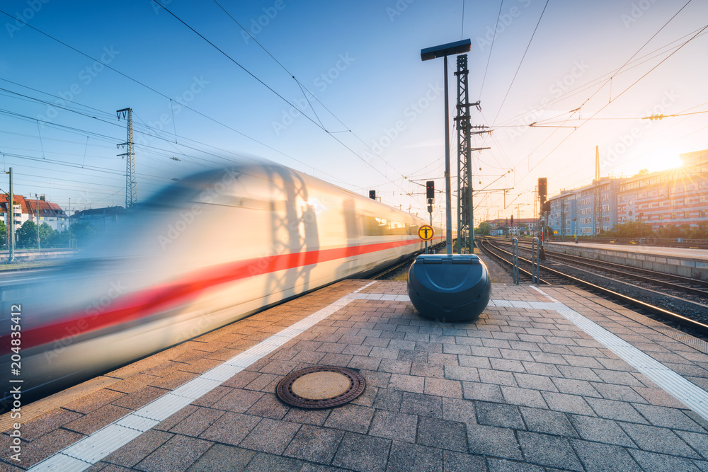 White high speed train in motion on the railway station at sunset. Germany. Blurred modern intercity