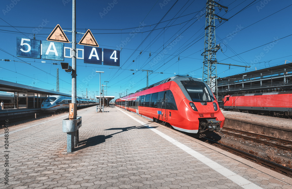 High speed red train on the railway station at sunset. Nuremberg, Germany. Modern intercity train on