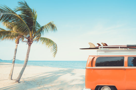 一辆停在热带海滩（海边）上的古董车，车顶上有冲浪板——休闲之旅
