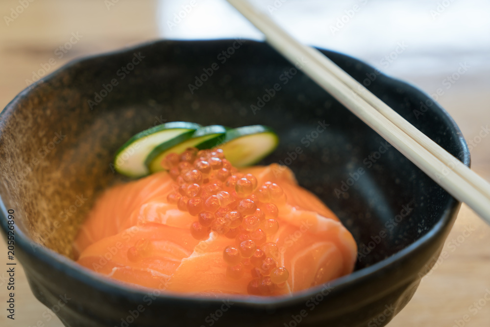 三文鱼Ikura Don-日本料理，三文鱼和Roe Rice Bowl在日本餐厅的餐桌上。