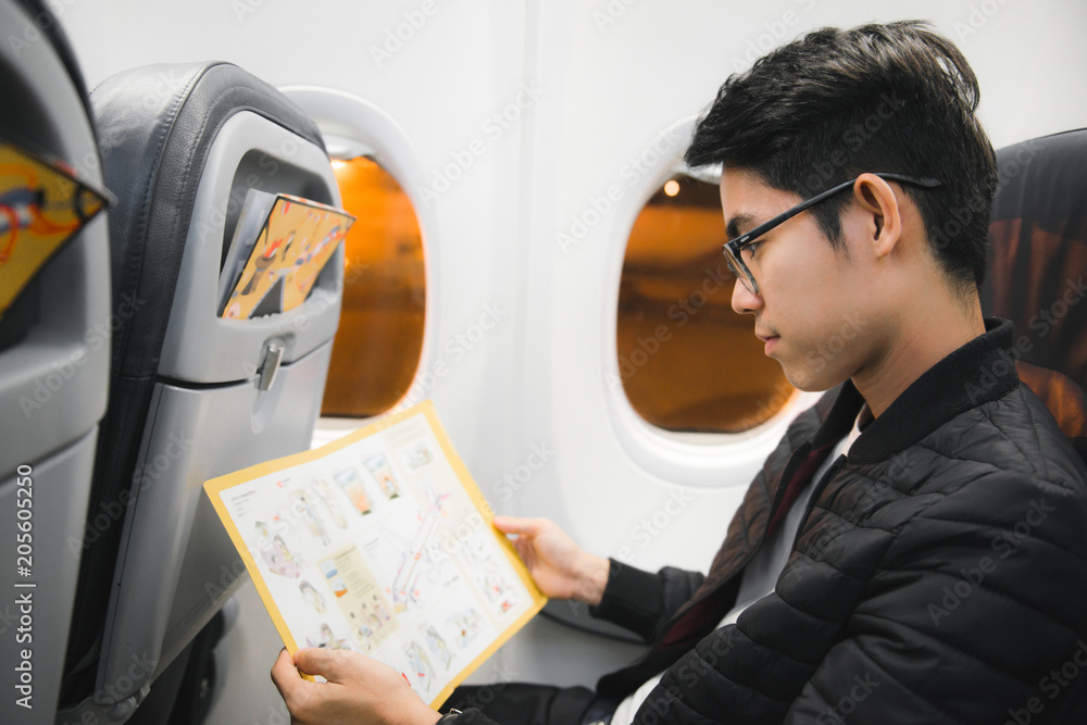 一名亚洲男子正在阅读机上安全信息提示卡