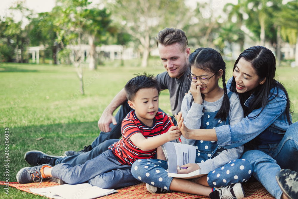 亚洲人和白种人的幸福家庭躺在花园绿地公园里玩耍和重新装修