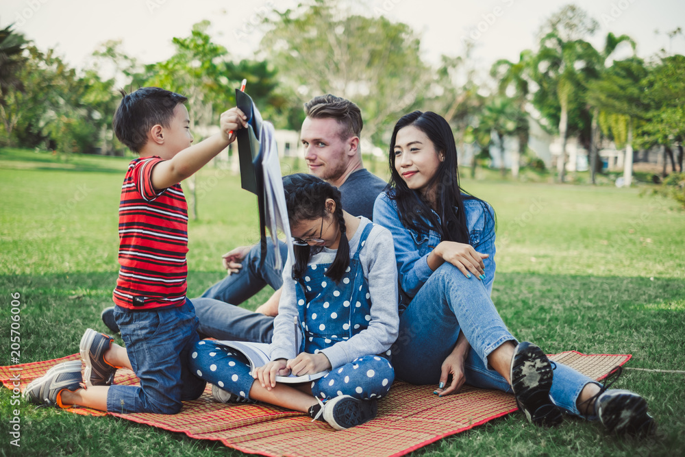 亚洲人和高加索人的幸福家庭躺在花园绿地公园户外玩耍和重新装修