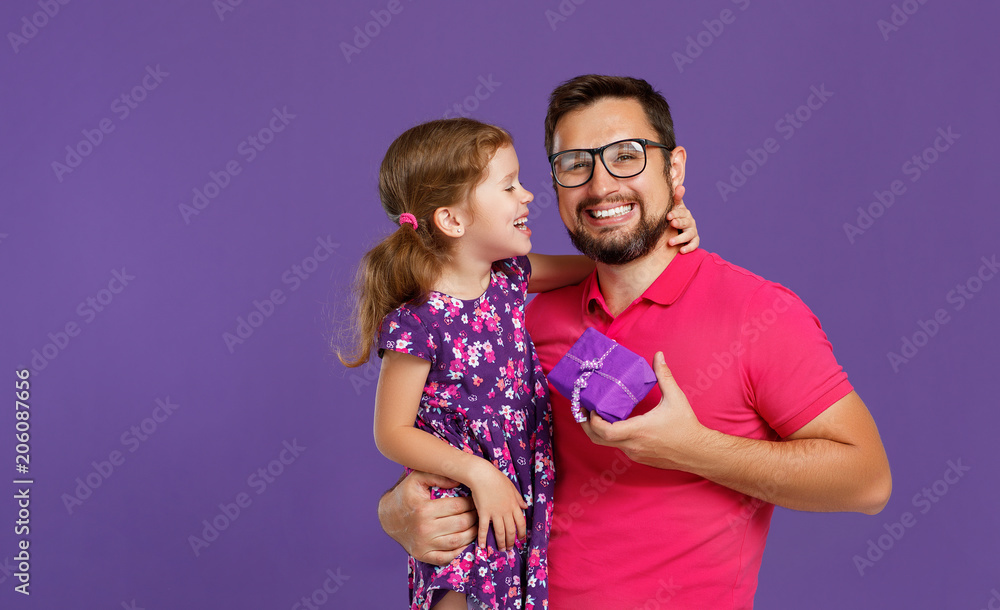 父亲节快乐！可爱的爸爸和女儿在紫色背景下拥抱。