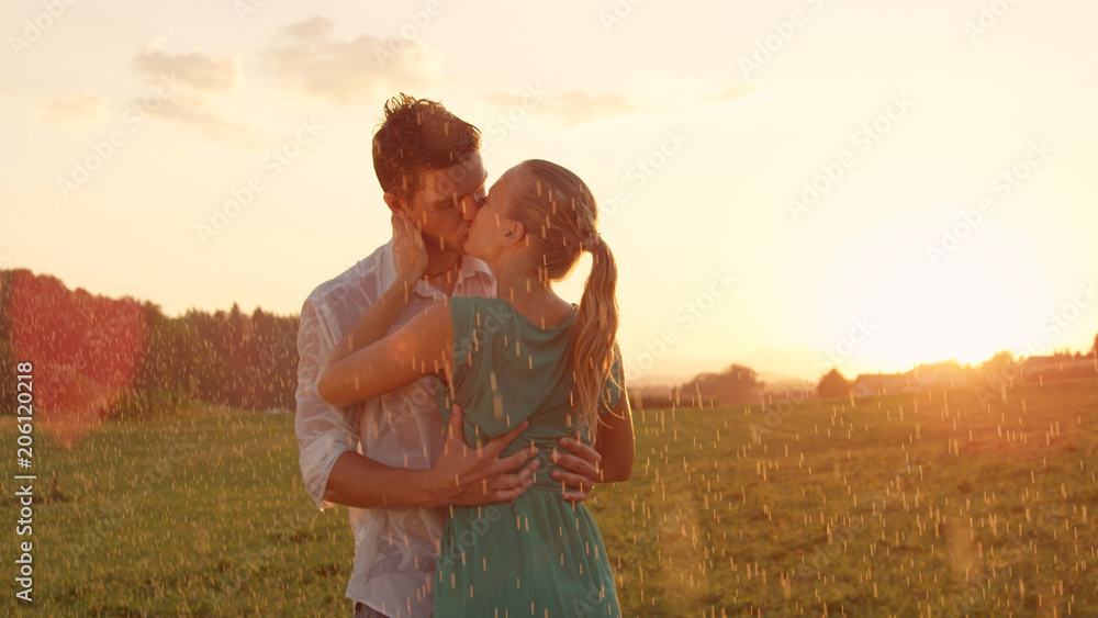 特写：一对年轻情侣在浪漫的户外约会中在雨中接吻。