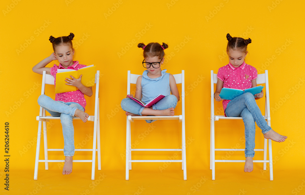 有趣的小女孩在黄色背景上看书