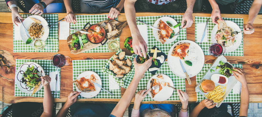 Family or friends summer party or outdoor dinner. Flat-lay of group of people at big table in cafe e