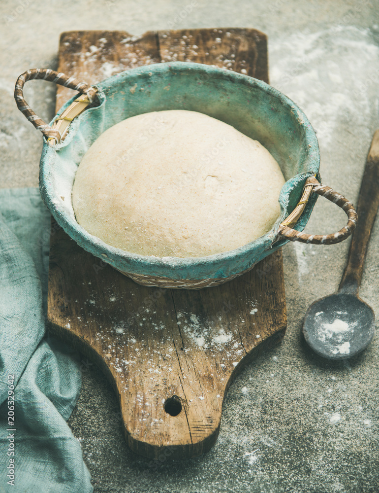 在灰色水泥厨房桌子背景上，在篮子里烤自制小麦粉面包的Sourdough