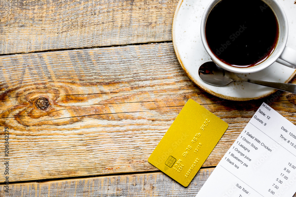 用信用卡和木桌上的咖啡支付餐厅账单