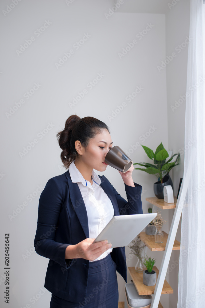 Young businesswoman on a coffee break. Using tablet computer.