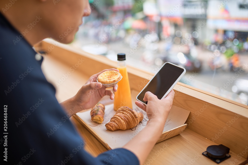 男性坐在露台咖啡馆时，通过智能手机在互联网网站上搜索所需信息