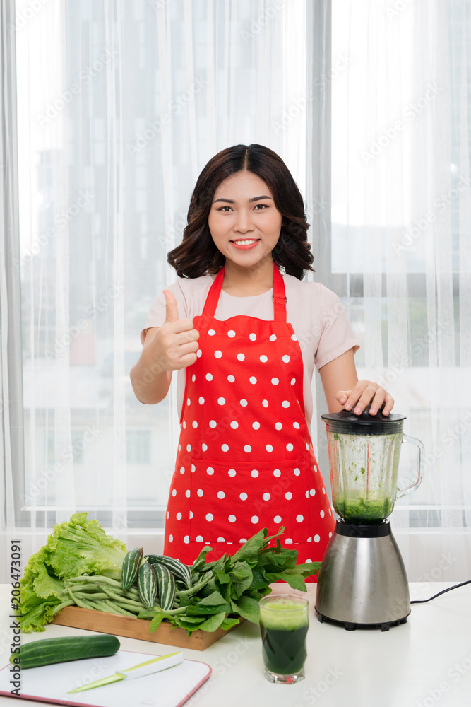 Young asian woman making green detox smoothie in kitchen at home.