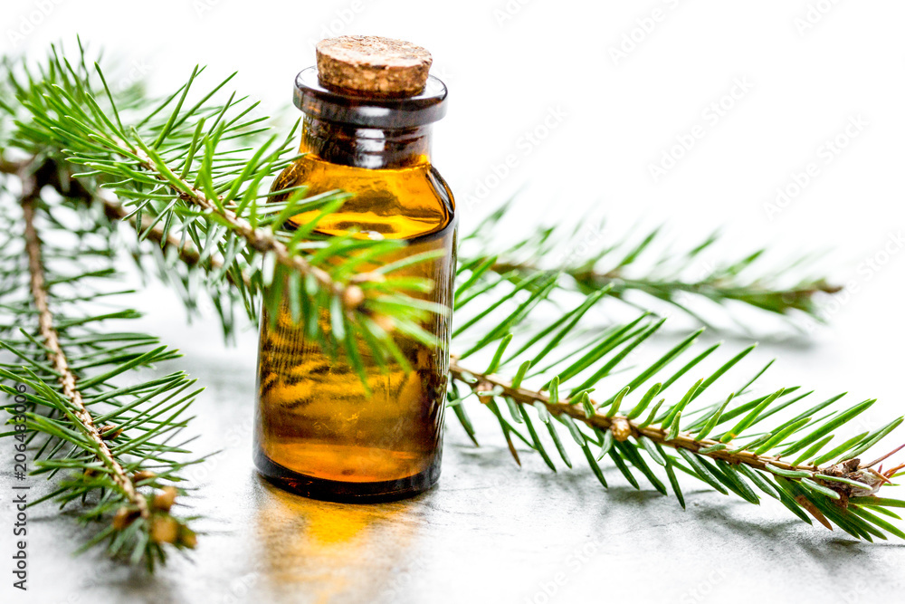 cosmetic spruce oil in bottles with fur branches on white table 