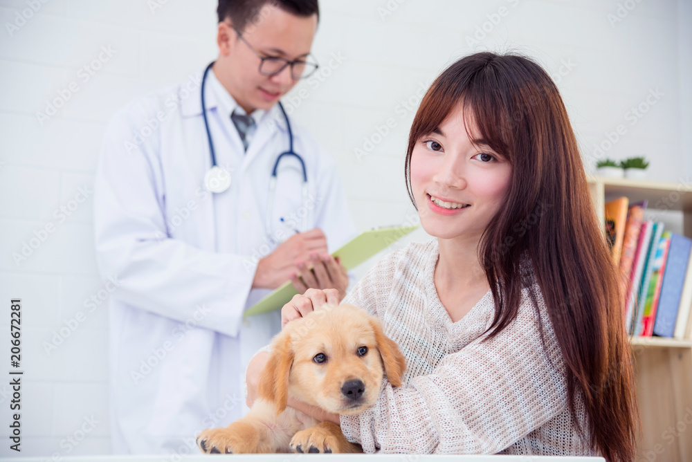 亚洲年轻女主人在兽医诊所与小狗合影，对着镜头微笑