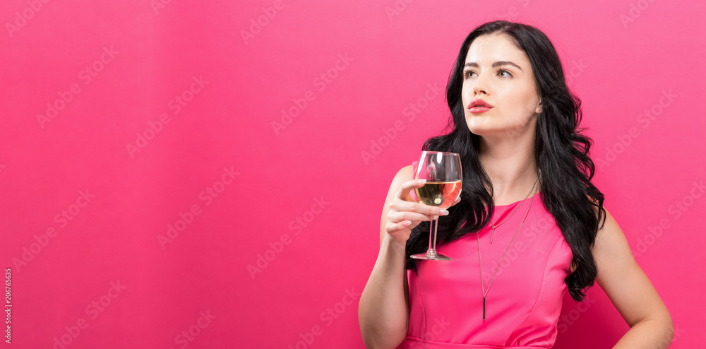 年轻女子在纯粉色背景下饮酒