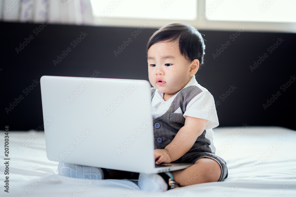 亚洲婴儿坐在工作服和笔记本电脑上，这个婴儿可以使用f