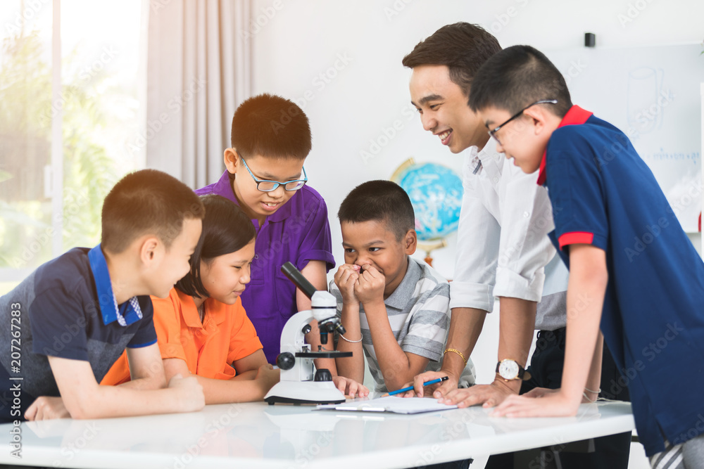 亚洲老师在生物课上用显微镜向学生拓展。