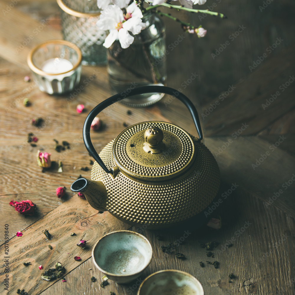 传统的亚洲茶道安排。金铁茶壶、杯子、干玫瑰、蜡烛和杏仁