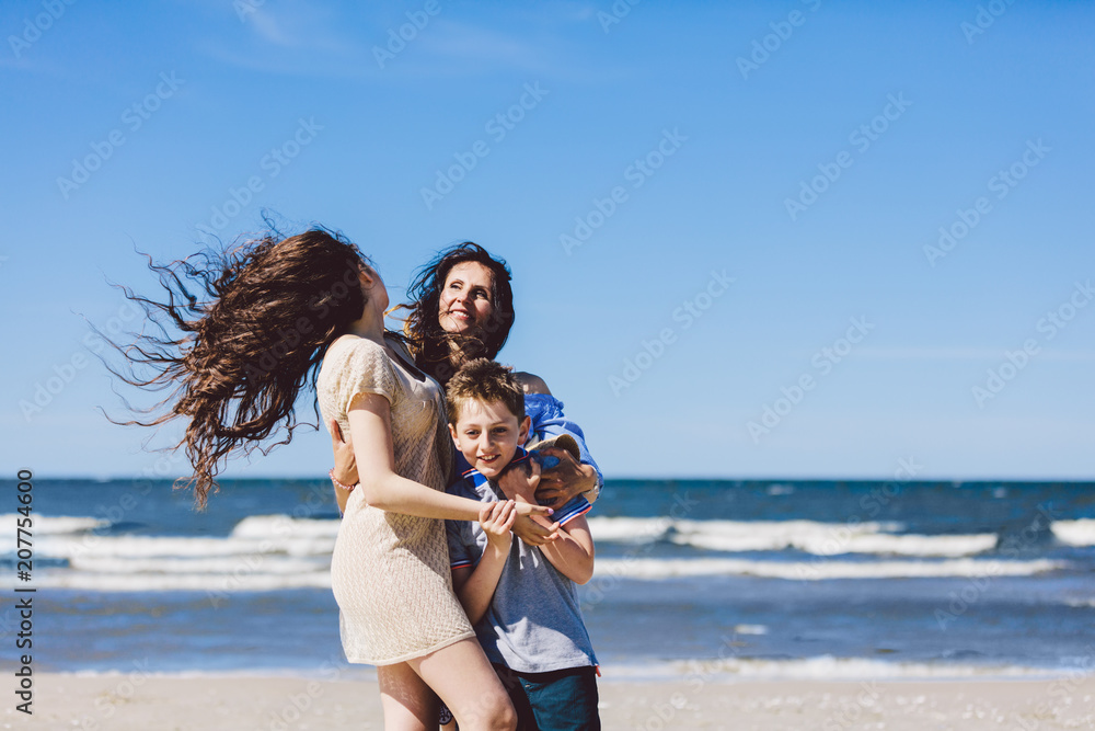 母亲和孩子拥抱并站在沙滩上