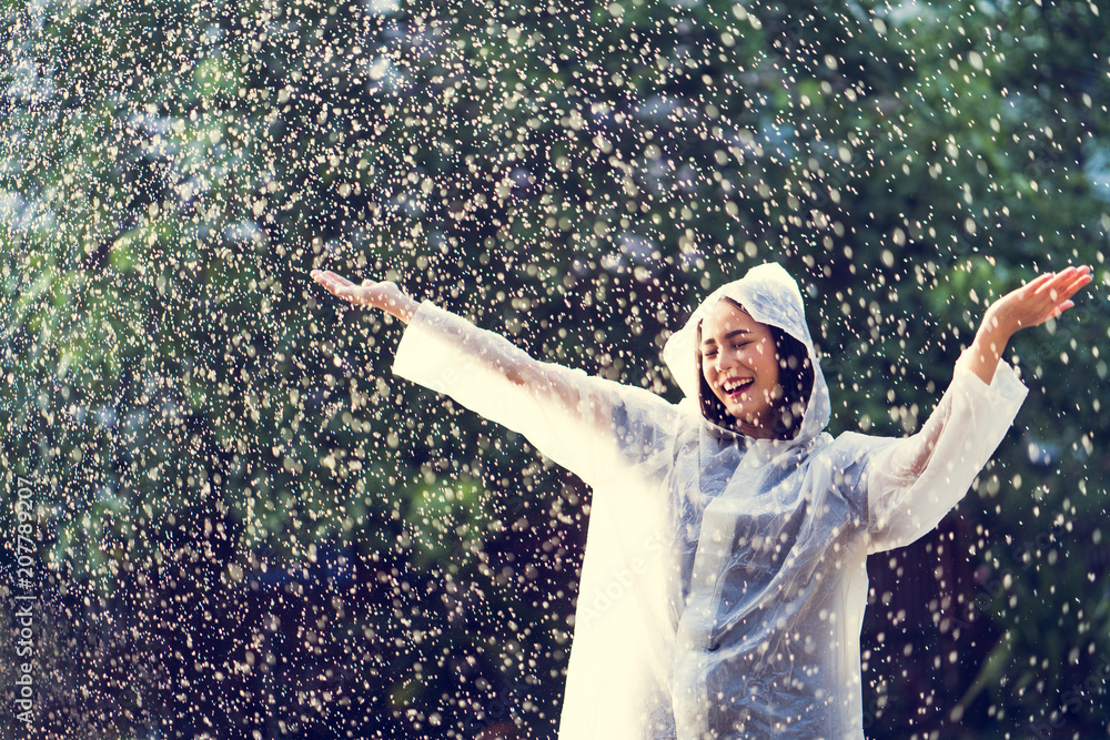 雨天，一个穿着雨衣的亚洲女人在户外。她很开心。