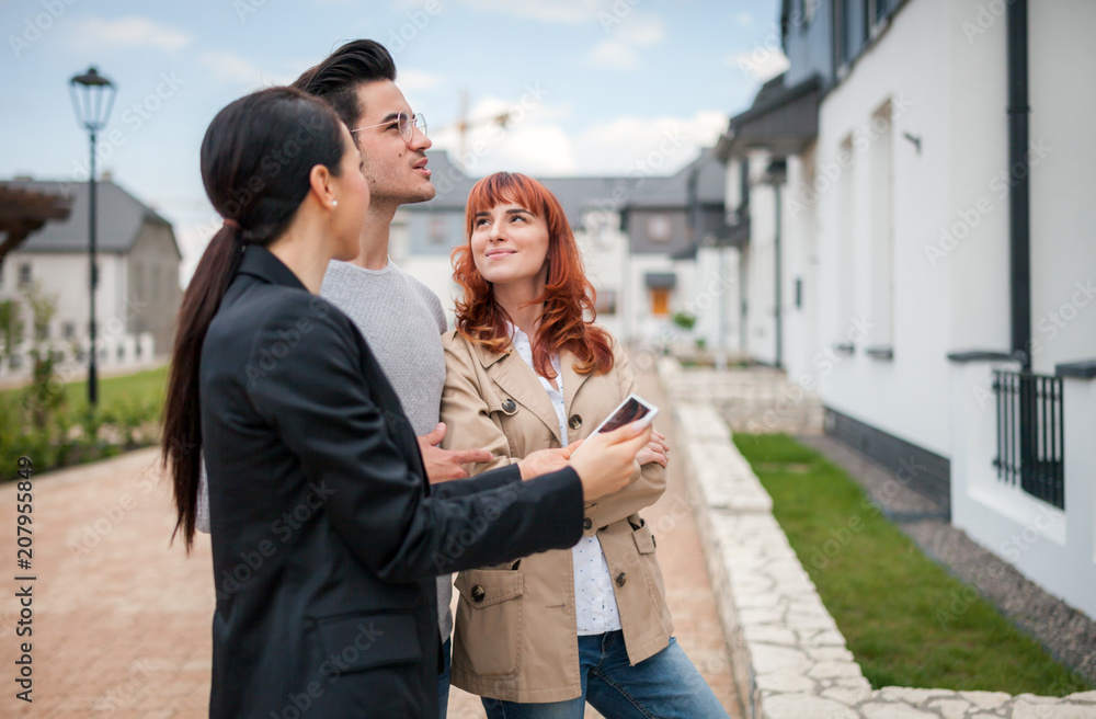 年轻夫妇与房地产经纪人参观住宅区待售房屋