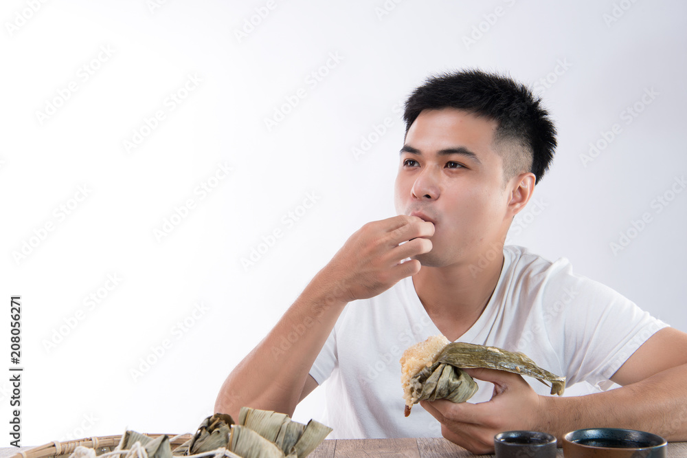 亚洲端午节，一名男子正在吃美味的粽子，感觉很美味。