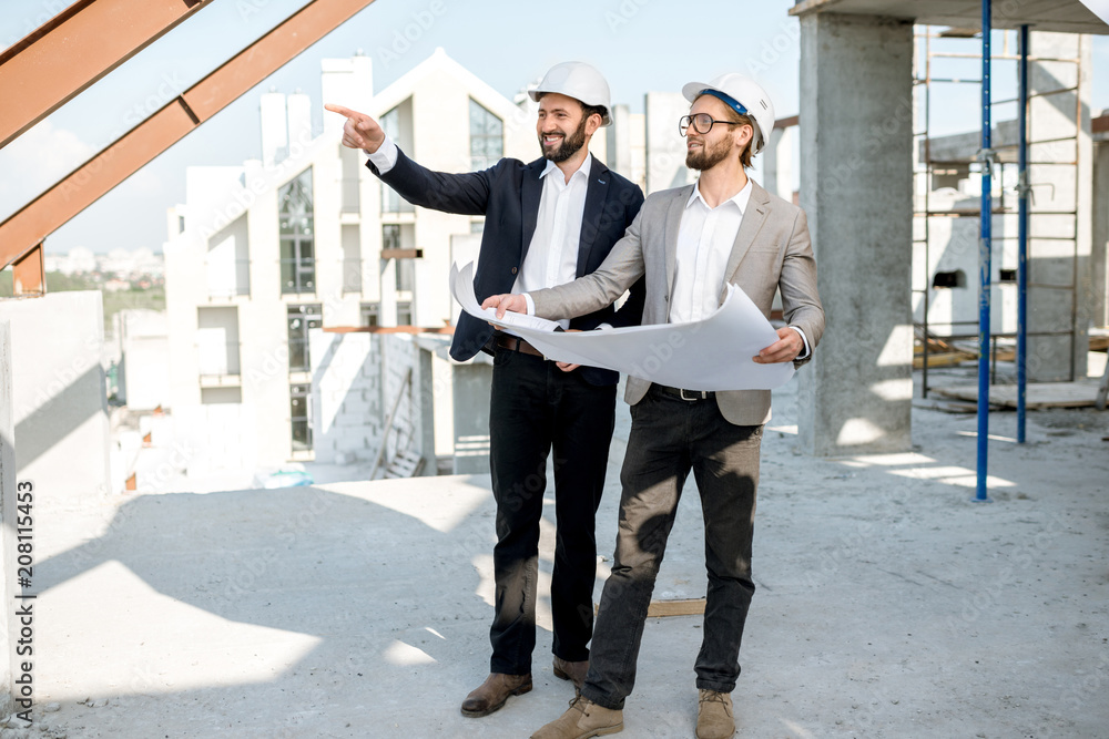 两名商务人员或工程师在施工期间处理结构上的房屋图纸