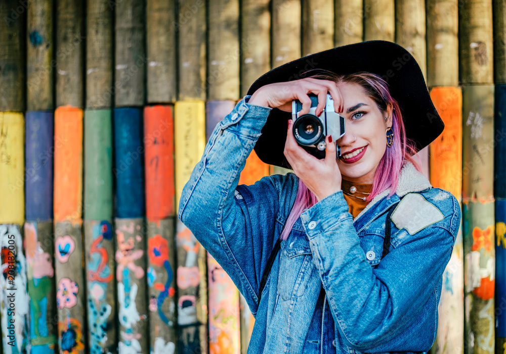 一位年轻的女摄影师站在彩色墙前的照片。