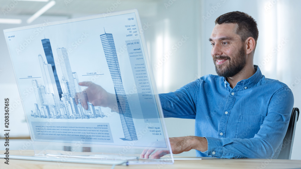 在未来派办公室，男性建筑师用摩天大楼B在透明电脑显示屏上工作