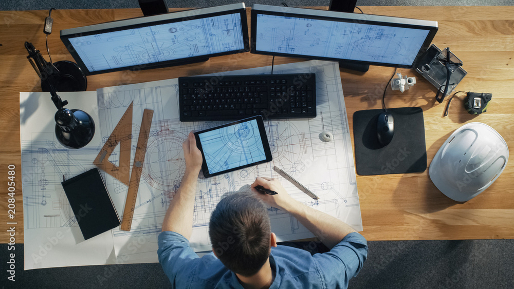 Top View of architectural Engineer Draws on His Blueprints, Compares with Tablet Computer with Green