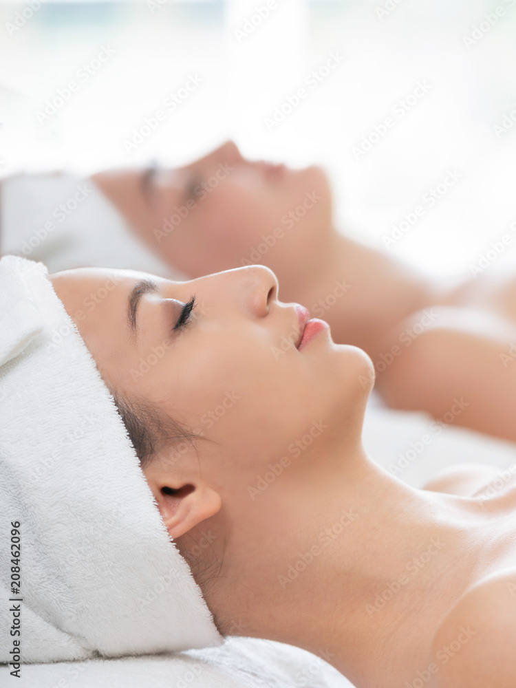 放松的年轻女子躺在水疗床上按摩。