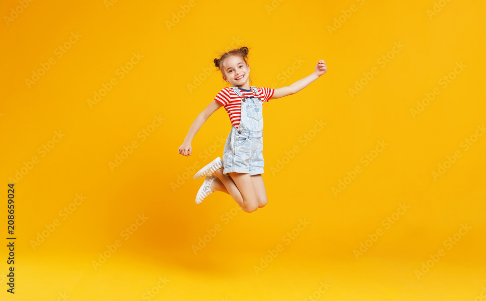 有趣的小女孩在黄色背景上跳跃