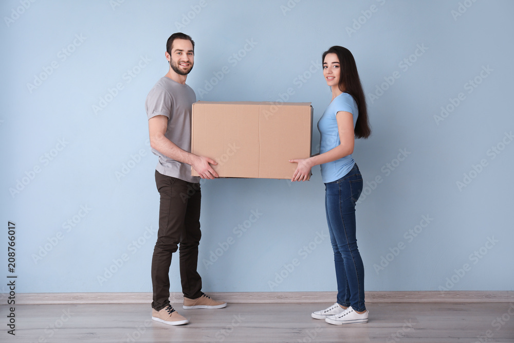 年轻夫妇带着盒子在室内。搬进新房子