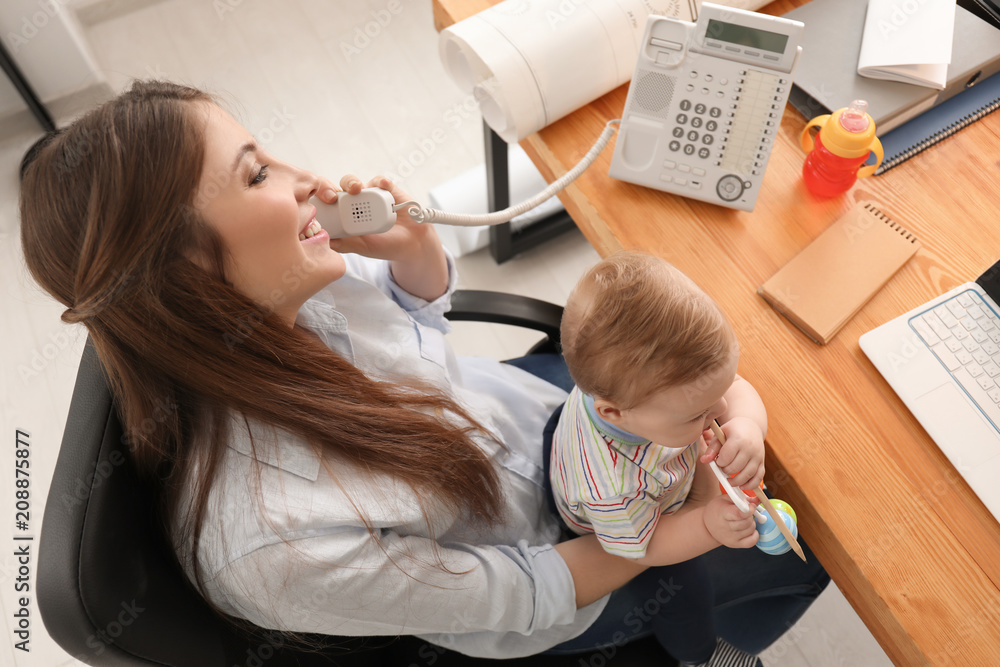 年轻母亲带着孩子在办公室工作时打电话
