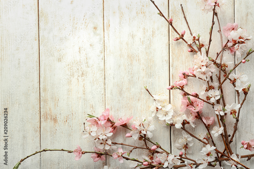 Beautiful blossoming branches on light wooden background