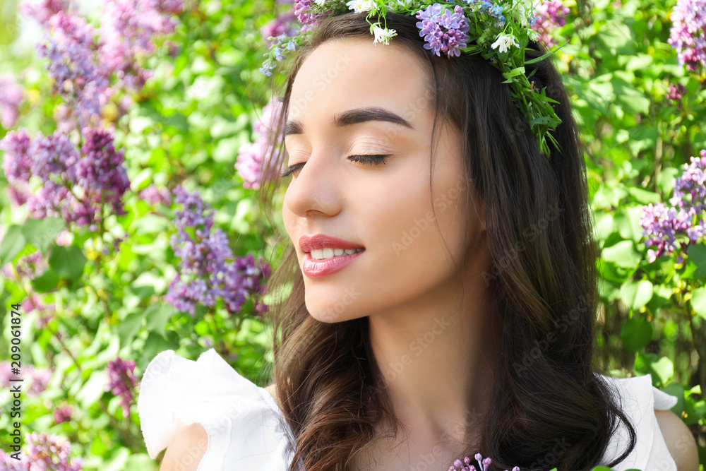 阳光明媚的春日，美丽的年轻女子在盛开的灌木旁戴着花环