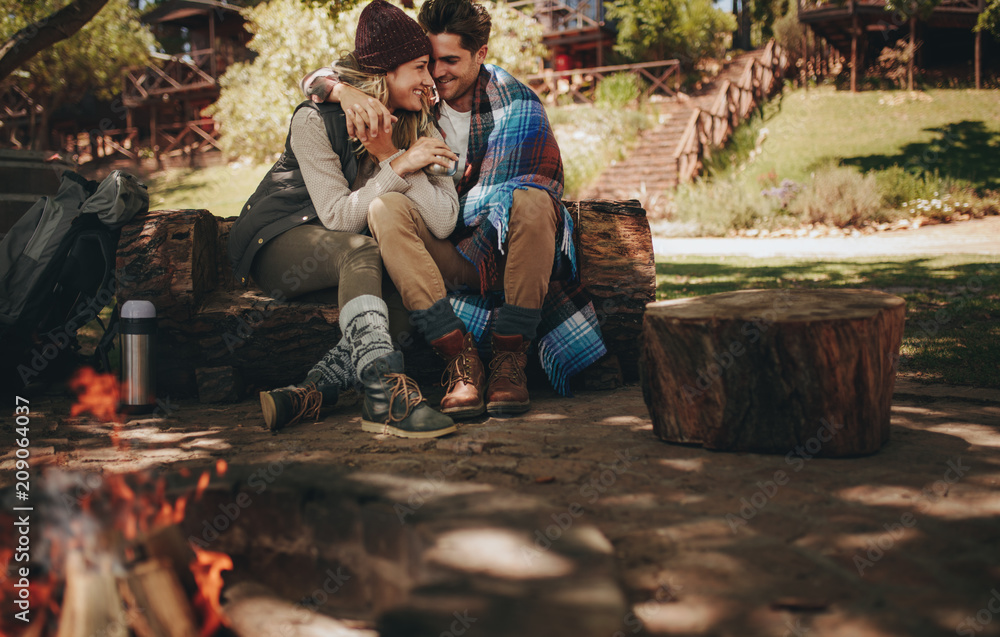 浪漫情侣坐在露营地篝火旁