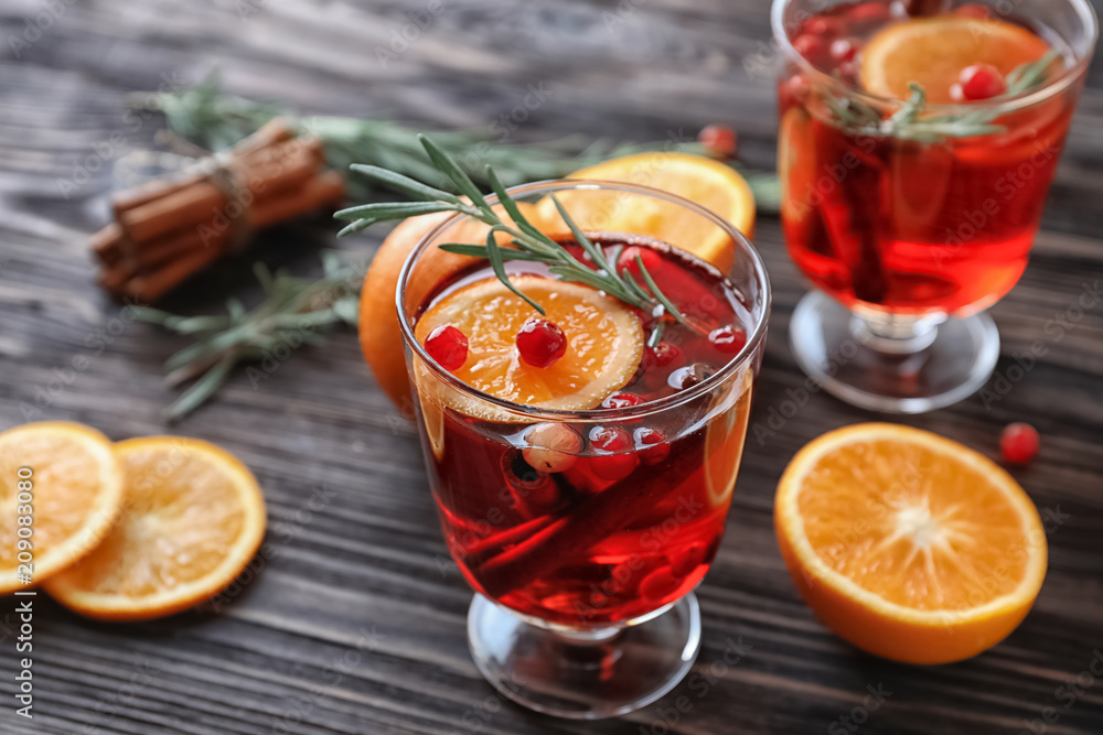 木制桌子上的玻璃里有肉桂、橙子和蔓越莓的饮料