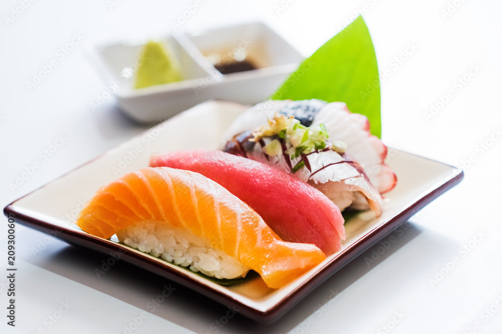 白色盘子上的寿司三文鱼、金枪鱼、寿司虾和芥末。选择性关注