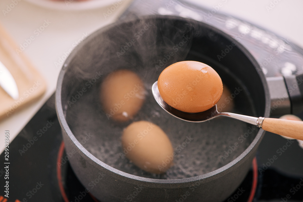 厨师把煮鸡蛋放在杯子里/烹饪甜棕色炖猪肉肉汁（Moo Pa lo）概念