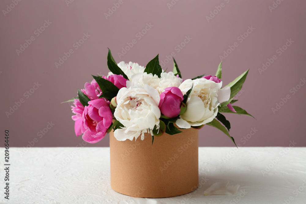 在彩色背景下，桌子上有美丽的牡丹花的盒子
