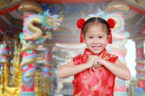 Little chinese girl in traditional Chinese cheongsam blessing for you in chinese new year festival.