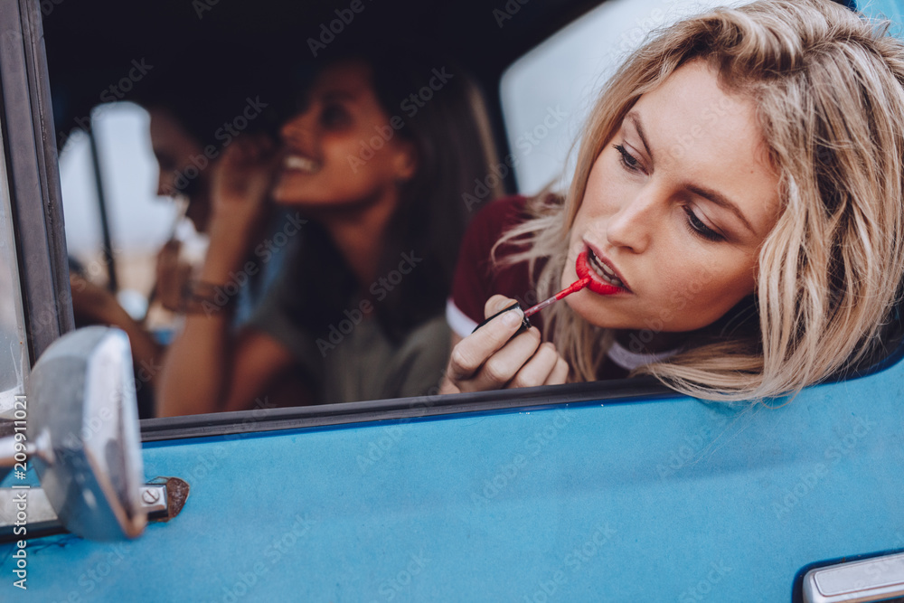 公路旅行中的女性在行驶的汽车里化妆