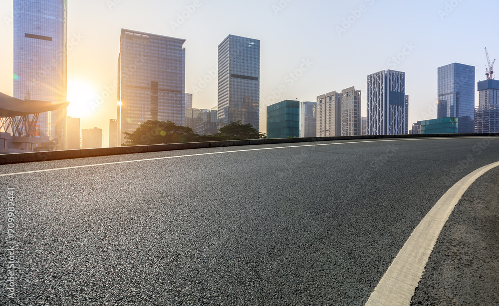 深圳日出时的空旷柏油路和现代城市商业建筑