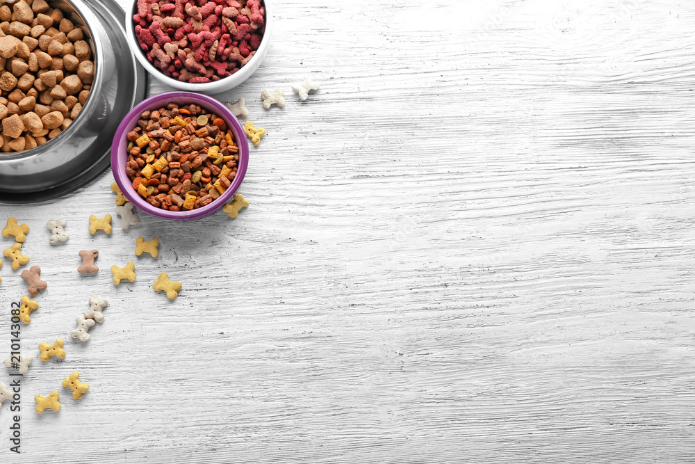 Bowls with pet food on wooden background