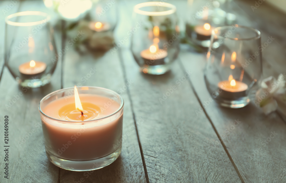 木桌上玻璃杯里燃烧的美丽蜡烛