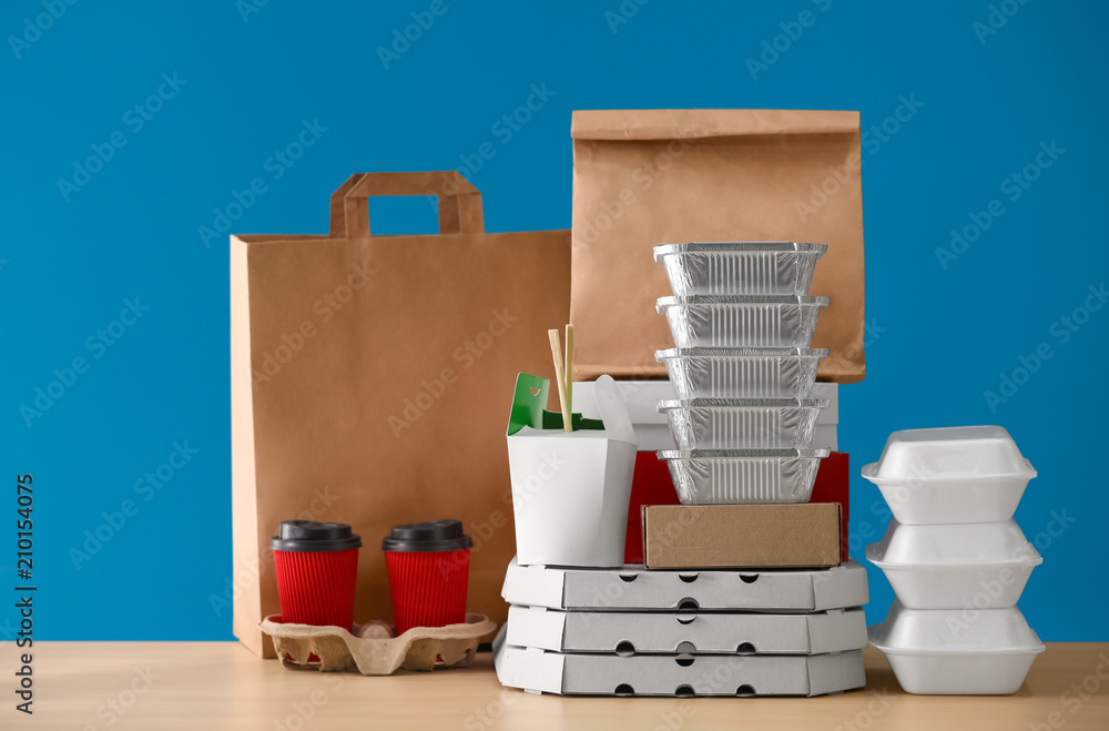 彩色背景下桌子上的不同包装和纸箱杯子。送餐服务