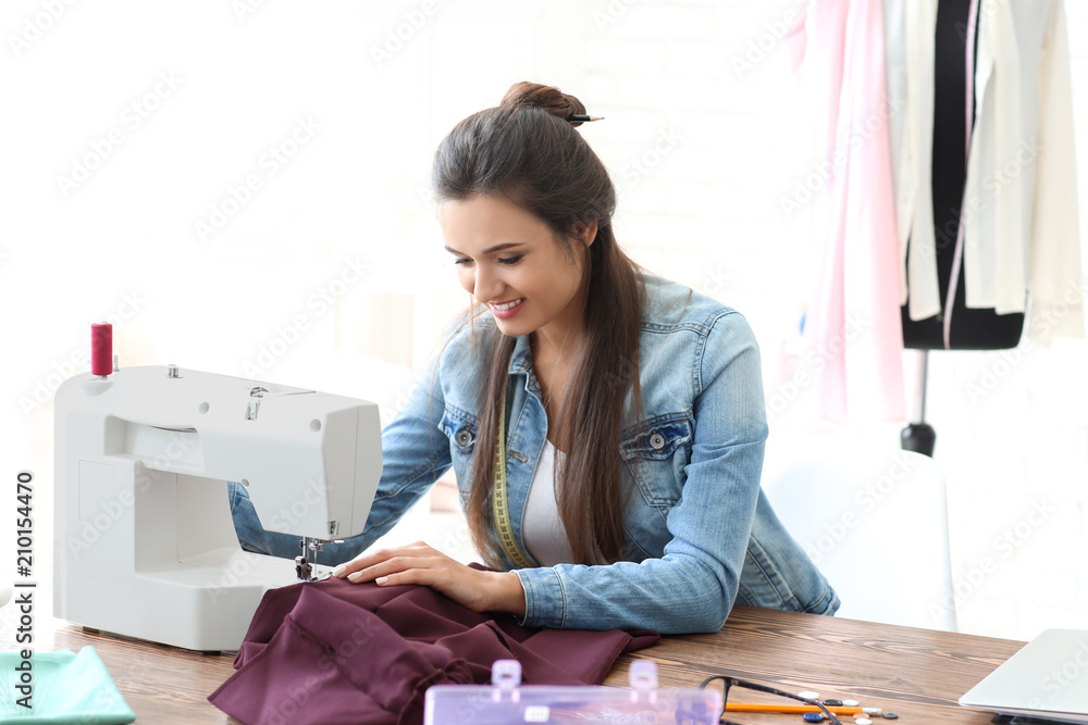 年轻的女裁缝在工作室使用缝纫机